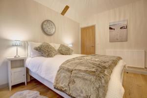 een slaapkamer met een bed en een klok aan de muur bij Owlets at Mulberry Barn in Heacham