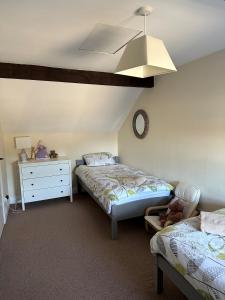 a bedroom with two beds and a dresser and a clock at Trotters Place - Bradwell in Bradwell