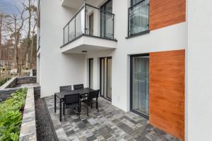 a house with a black table and chairs on a patio at Pobierowo Beach Baltic Apartment with Pool by Noclegi Renters in Pobierowo