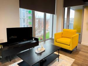 a living room with a yellow chair and a television at 2bed on Elizabeth line-5mins to Excel Custom House in London