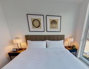 a bedroom with a large white bed with two lamps at Level Long Beach - East Village in Long Beach