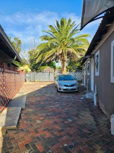 un coche aparcado en una entrada con una palmera en Reutlwane Gardens Guesthouse en Secunda