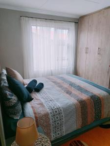 a bedroom with a bed with a blanket and a window at Reutlwane Gardens Guesthouse in Secunda