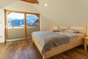 a bedroom with a bed and a large window at Apartments and Rooms Hodnik Slavko in Bohinj
