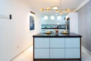 a kitchen with white cabinets and a black counter top at 10 mint drive to Mid Valley KL near Gateway Bangsar Seputeh in Kuala Lumpur