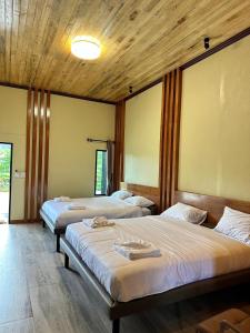 three beds in a room with wooden ceilings at Phangnga Save House - เซฟเฮาส์พังงา in Phangnga