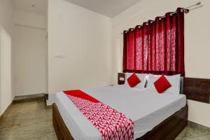 班加羅爾的住宿－OYO 82074 Hotel Aishwarya Comfort，一间卧室配有一张带红色窗帘的大床