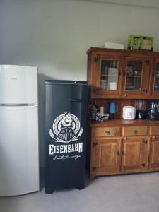 a kitchen with a refrigerator and wooden cabinets at Pousada Lobo Guará in São João Batista do Glória