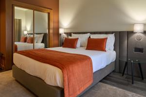 um quarto de hotel com uma cama grande com almofadas laranja em Hotel Versatile na Guarda mais 37 fotografias