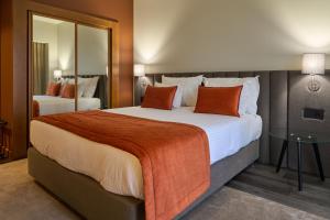 a hotel room with a large bed with orange pillows at Hotel Versatile in Guarda