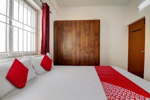 班加羅爾的住宿－OYO 82074 Hotel Aishwarya Comfort，一间卧室配有一张带红色和白色枕头的大床