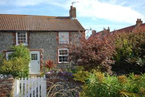 una casa de ladrillo con una valla blanca delante de ella en Romany Rye, en Sheringham