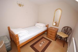 1 dormitorio con cama, espejo y silla en Romany Rye, en Sheringham