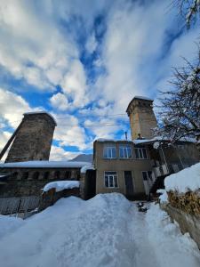 a house with two towers in the snow at Guest House Ketevan Niguriani in Mestia