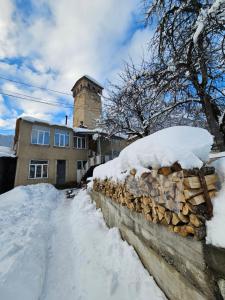un muro di pietra ricoperto di neve di fronte a una casa di Guest House Ketevan Niguriani a Mestia