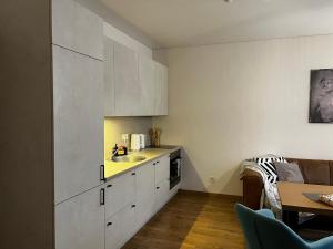 a kitchen with white cabinets and a sink and a table at Kauno Senamiestis in Kaunas