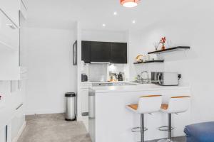 a white kitchen with a counter and two stools at High Spec 2 Bed, 2 Bath, Wi-Fi, Balcony in Hemel Hempstead