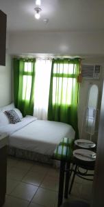 una camera da letto con un letto con tende verdi e un tavolo di Pierrecondotel a Manila