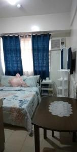 een slaapkamer met een bed en een tafel en blauwe gordijnen bij Pierrecondotel in Manilla