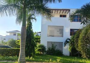 a palm tree in front of a white building at Haradali Suites 2 Bedroom Beach Apartment - Sultan Palace Beach Resort in Kilifi
