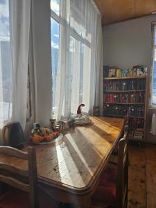 a wooden table in a room with a large window at Guest House Ketevan Niguriani in Mestia