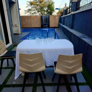 a table and chairs on a patio with a pool at ReUnion Villa ll Swimming Pool ll Snooker ll AC ll BBQ ll 3BHK in Lonavala