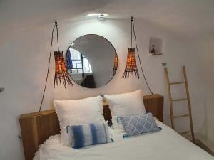 a bedroom with a mirror and a bed with pillows at L'Exquishette de Lourmarin, un nid sur les toits. in Lourmarin