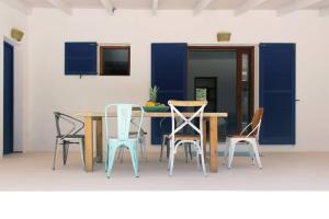 a table and chairs in a room with blue shutters at A beautiful villa close to the beach in Playa Migjorn