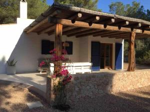a porch of a house with a bench and flowers at A beautiful villa close to the beach in Playa Migjorn
