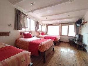 Habitación con 3 camas, sábanas rojas y ventanas. en La Casa de Mayte, en Cusco