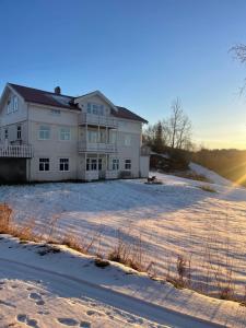 a large white house in the snow with the sun setting at Spacious apartment in beautiful Norway countryside close to trondheim fjord 