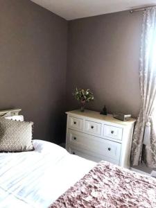Beautiful holiday flat in Alnwick في ألنويك: غرفة نوم بها سرير وخزانة وعليها زهور