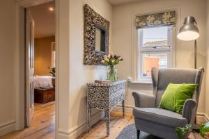 a living room with a chair and a table with a vase of flowers at Norfolk House 2 in Heacham