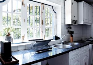 eine Küche mit einem Waschbecken und zwei Fenstern in der Unterkunft Casa de Travassos in Luzim