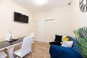 a living room with a blue couch and a table at Barking Road Comfy House in London