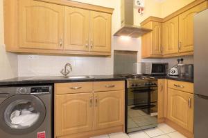 a kitchen with wooden cabinets and a washing machine at Barking Road Comfy House in London