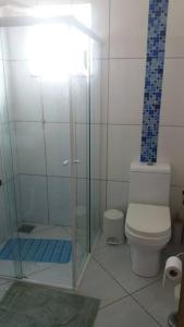 a bathroom with a toilet and a glass shower at Linda casa de praia 5km Beto Carrero - Gravatá. 300 metros da praia!! in Navegantes
