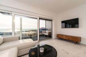 ein Wohnzimmer mit einer Couch, einem Fernseher und einem Tisch in der Unterkunft Mina stunning sea view apartment in Novalja