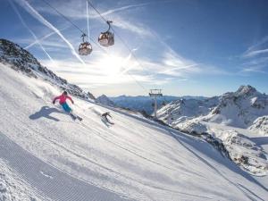 two people skiing down a snow covered mountain with a ski lift at Tiny House nähe Millstättersee mit Hot Tub in Oberkolbnitz