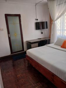 Dormitorio con cama, escritorio y TV en Annodas Homes Milimani Kisumu en Kisumu
