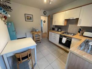 una cocina con armarios blancos, una mesa y una barra en Beautiful 2 bedroom apartment with estuary views, en Deganwy 7 fotos más