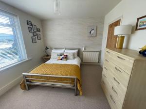 a small bedroom with a bed and a dresser at Beautiful 2 bedroom apartment with estuary views in Deganwy