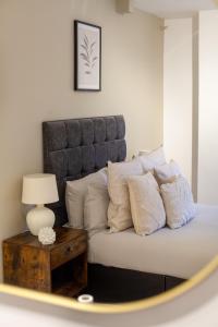a bed with pillows and a table with a lamp at The Maida Vale Flat in London