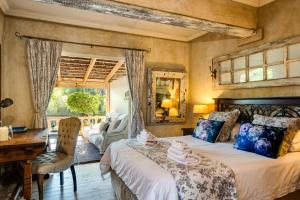 een slaapkamer met een bed, een bureau en een raam bij Petite Provence B&B in Ballito