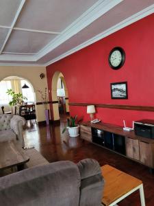 uma sala de estar com uma parede vermelha e um relógio em Annodas Homes Milimani Kisumu em Kisumu