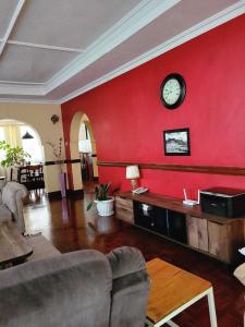 a living room with a red wall with a clock at Annodas Homes Milimani Kisumu in Kisumu