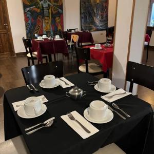 una mesa con platos y cubiertos de plata sobre un mantel negro en Hotel Texas en Cafayate