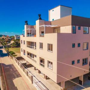 Un grand bâtiment blanc avec des fenêtres donne sur une rue. dans l'établissement Cobertura em Bombinhas - Piscina - Luxo - Alto Padrão, à Bombinhas