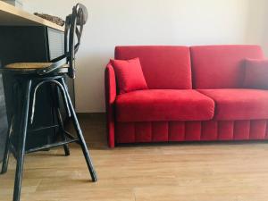 a red couch and a stool in a living room at Charmant T2 au cœur de la ville in Furiani