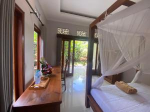 a bedroom with a canopy bed and a door to a yard at GUS ARDITYA HOMESTAY in Ubud